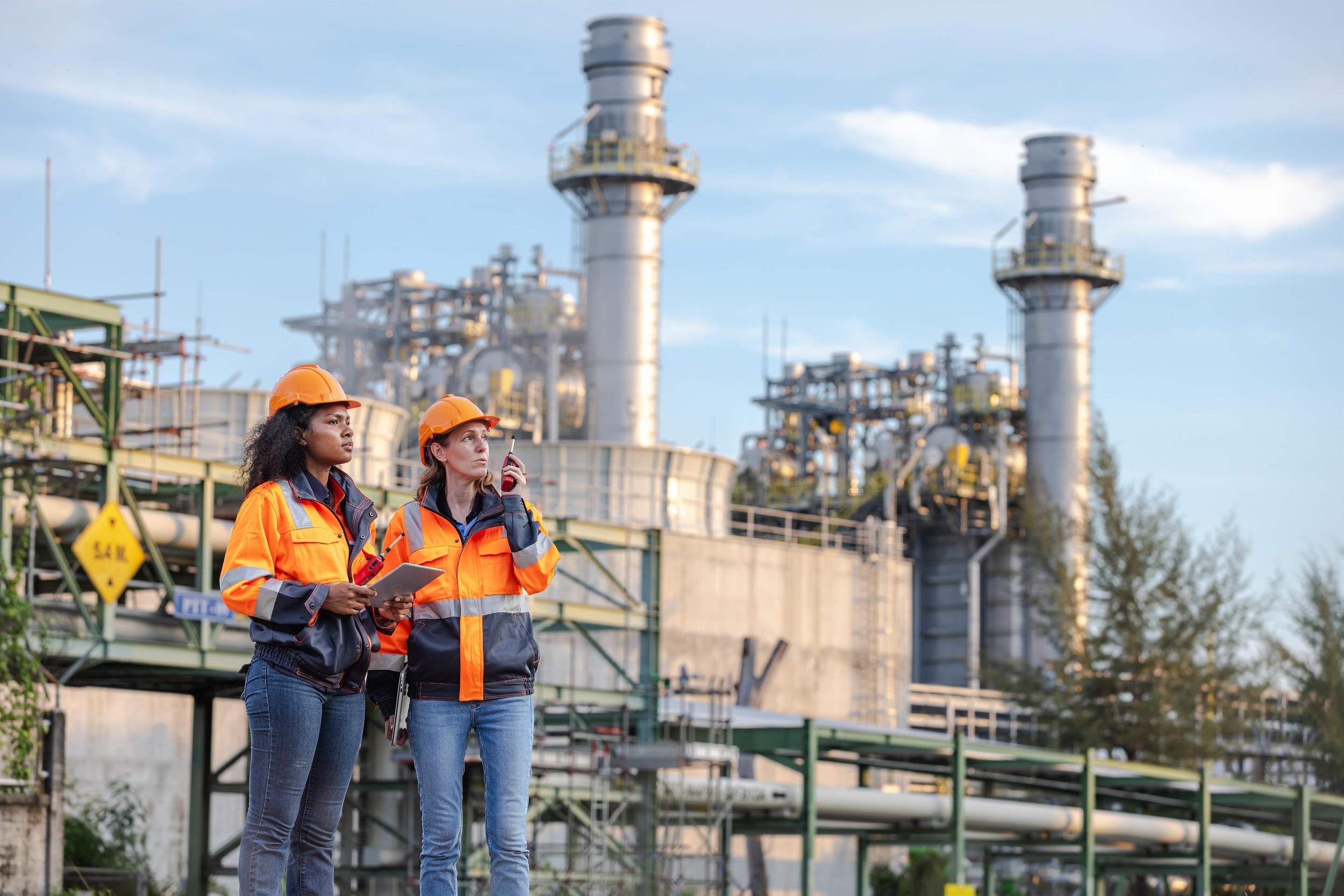 Engineers Inspecting Operations at a Water Pumping Station with Large Pipes and Industrial Towers